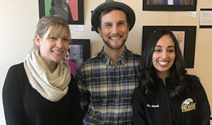 Two women and a man standing together in a group
